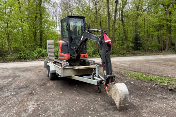A Small Excavator Standing On A Car Trailer Rests Its Bucket On The Ground.
